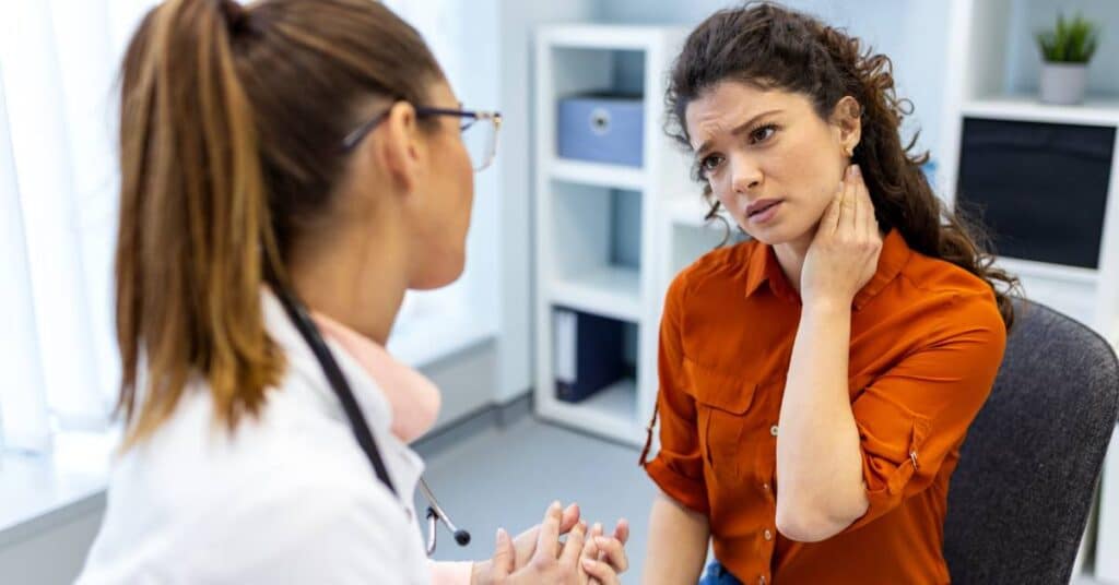 Patient explaining neck pain to a healthcare provider during a medical appointment, showing how to describe your symptoms clearly.