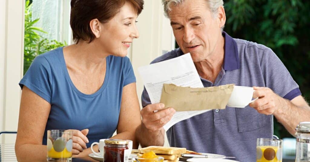 Couple reviewing medical paperwork at home while discussing a prior authorization delay for a recommended treatment.